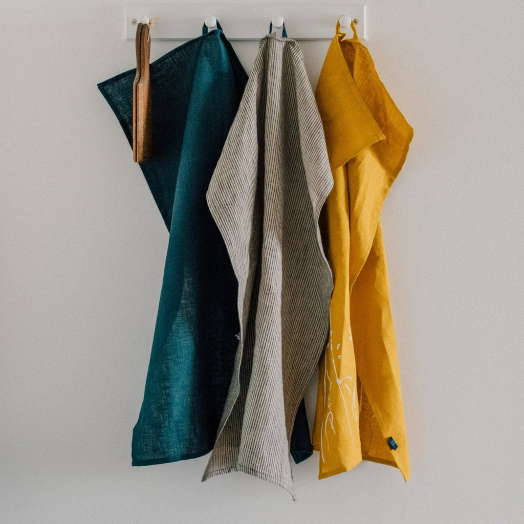 Pure linen tea towels by Helen Round. Mustard tea towel, Navy blue tea towel and striped tea towel hanging up