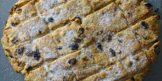 Cornish Hevva Cake on a wooden board with a cup of tea