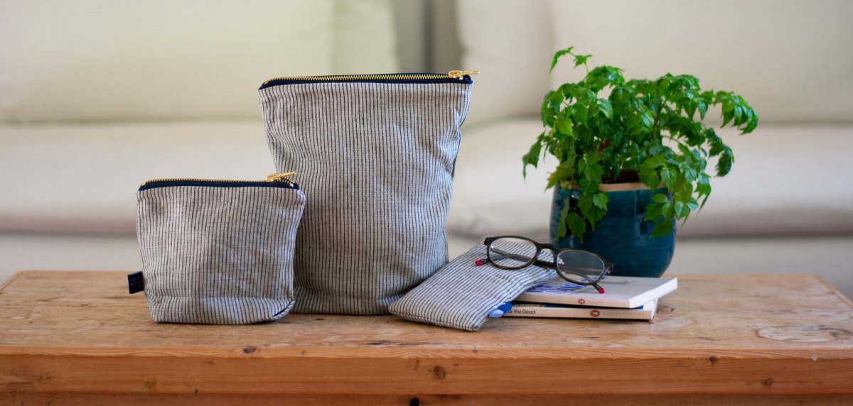 Blue and Cream Fine Striped Linen Toiletry Bag, Wash Bag and Glasses Case on wooden counter, from Helen Round