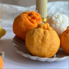 Decorative candles shaped like fruits on a white surface with a neutral background