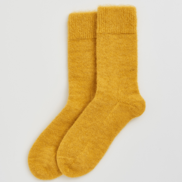 Pair of mustard yellow socks on a light gray background