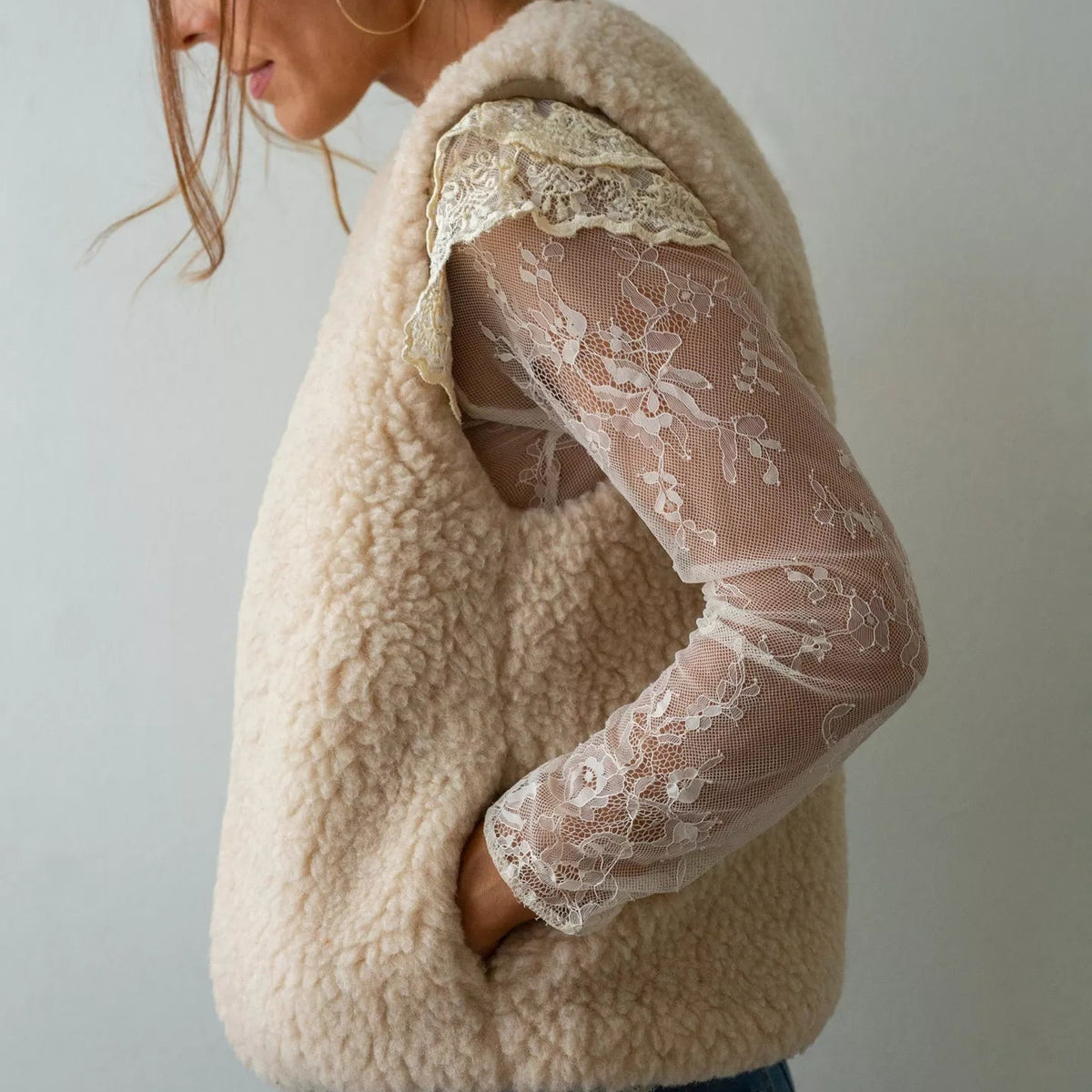 A woman wearing a cream-colored Merino woo  vest sold by Helen Round