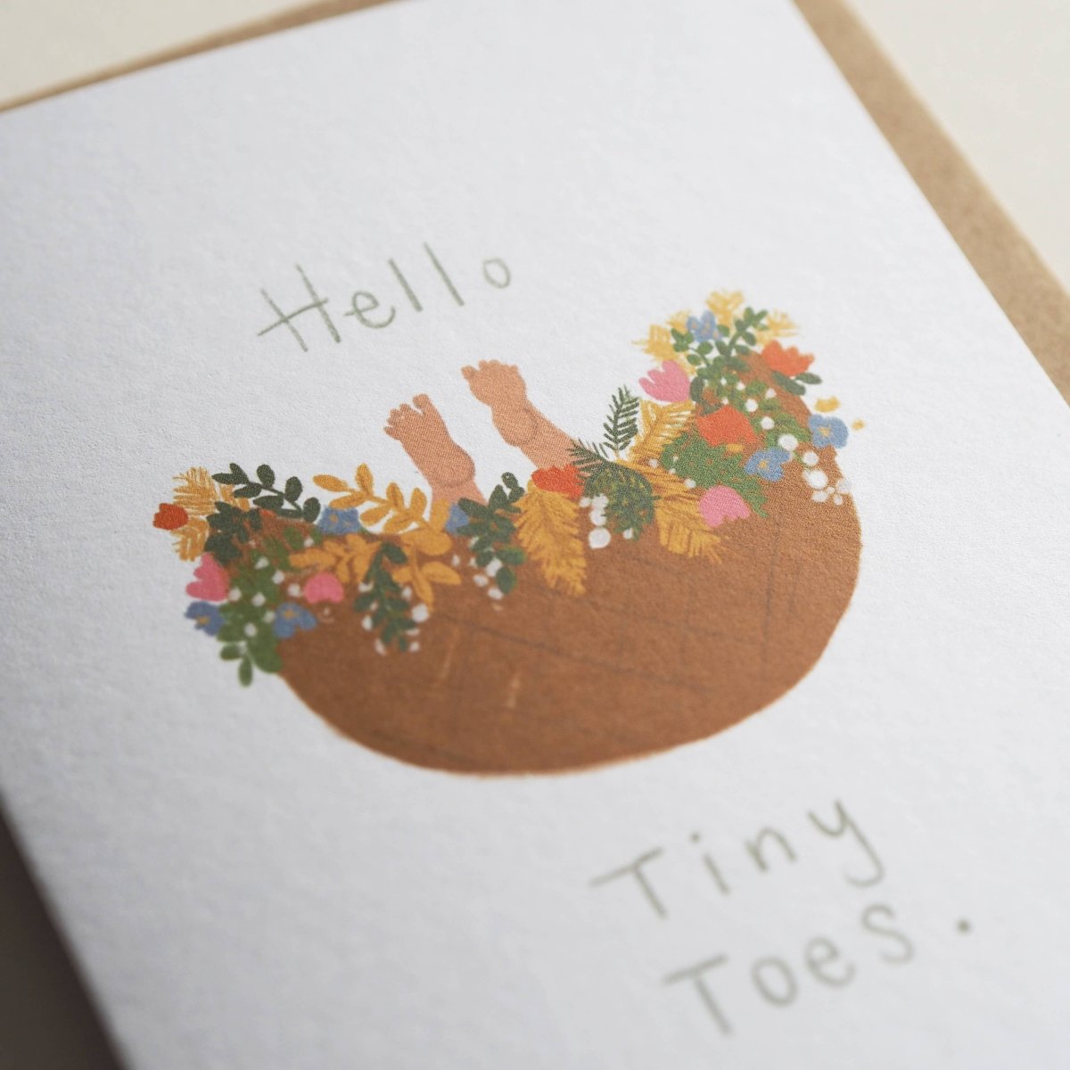 Greeting card with illustration of feet in a flower pot and text 'Hello Tiny Toes' on a white background  sold by Helen Round