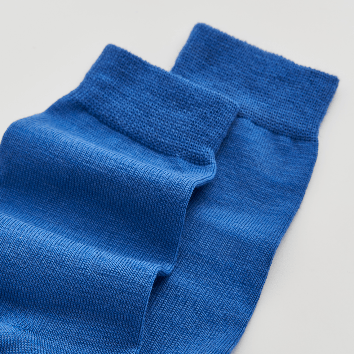 Pair of blue socks on a light gray background