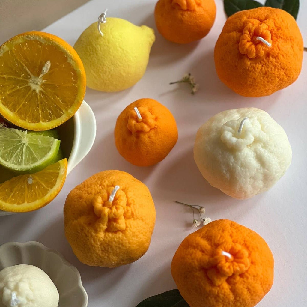 Decorative candles shaped like fruits on a white surface