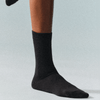 Black merino wool socks worn by a person on a light grey background