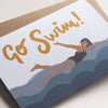 Greeting card with 'Go Swim!' text and a swimmer illustration on a white background sold by Helen Round