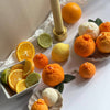 Assorted citrus fruits, including oranges, lemons, and lime candles  on a white surface.