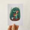 Illustration of a person holding a plant in a pot on a postcard held by a hand. Sold By Helen Round