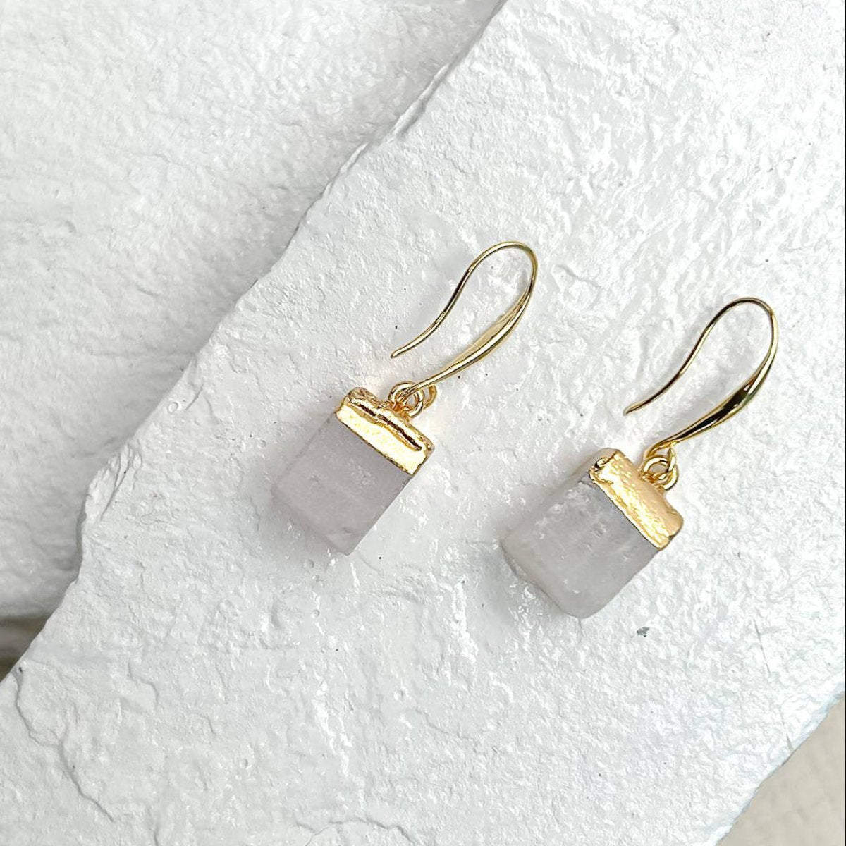 Gold earrings with a Quartz Cube on a textured white surface sold by Helen Round