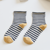 Pair of striped socks with gold toes on a light surface Sold by Helen Round