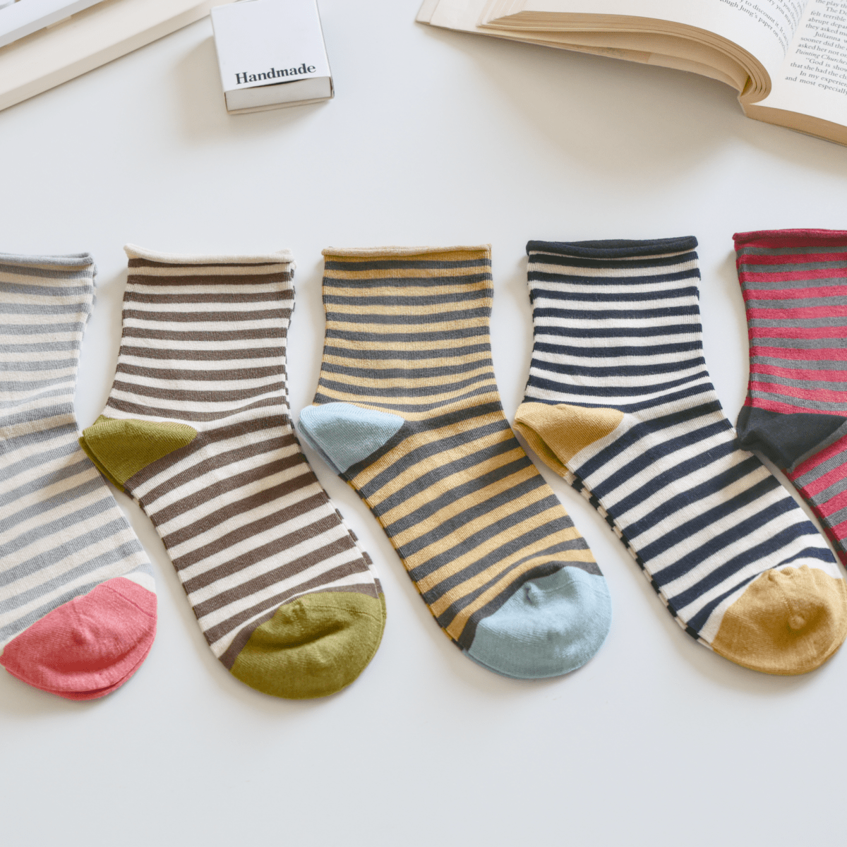 Colorful striped socks on a light surface with a keyboard and book in the background sold by Helen Round