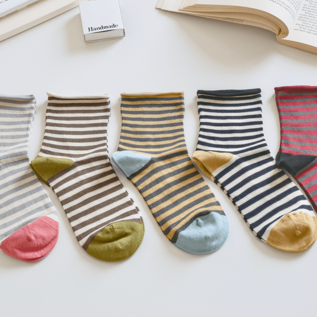 Colorful striped socks on a light surface with a keyboard and book in the background sold by Helen Round