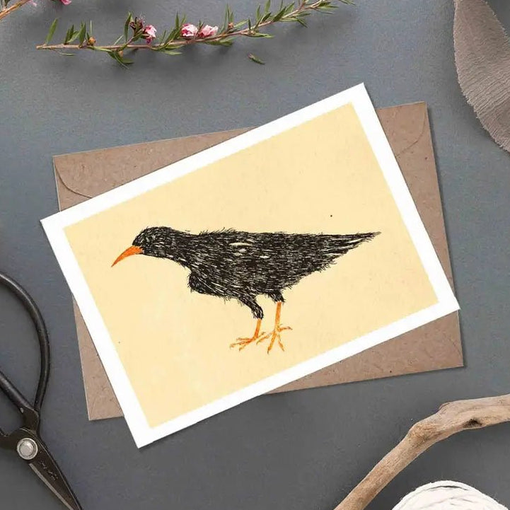 Greeting card with a bird illustration on a gray surface with decorative items.