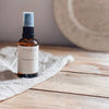 Bottle of mokse cleansing oil on a wooden surface with a neutral background