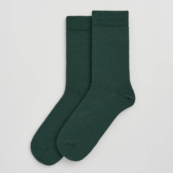 Pair of dark green socks on a light gray background