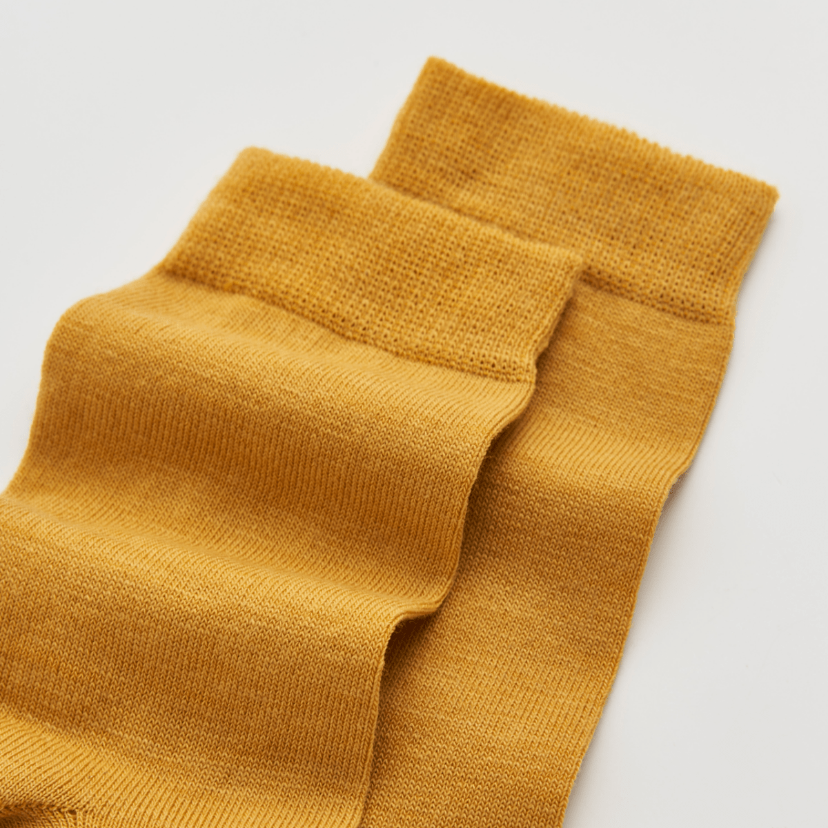Mustard yellow socks on a light gray background