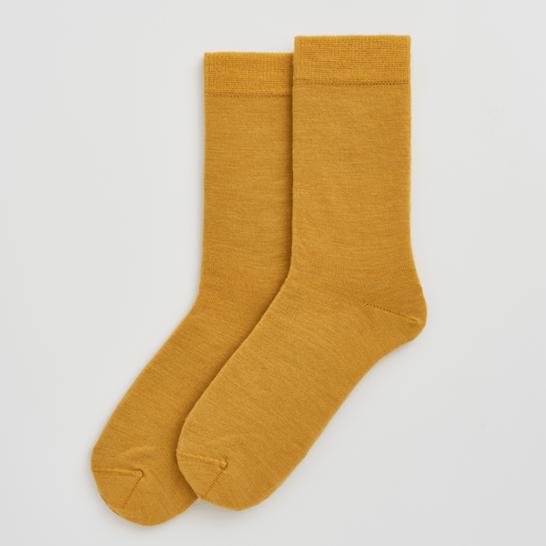 Pair of mustard yellow socks on a light gray background