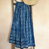Blue patterned sarong and straw hat on a wooden ladder against a beige wall
