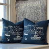 Two blue linen pillows with white illustrations of houses and boats on a windowsill by Helen Round