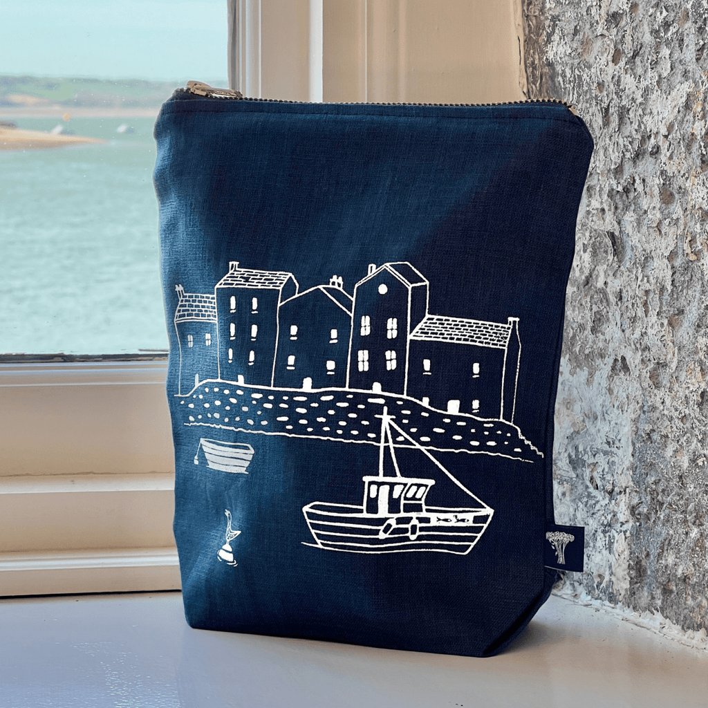 Navy linen pouch with white illustration of a coastal scene on a windowsill.