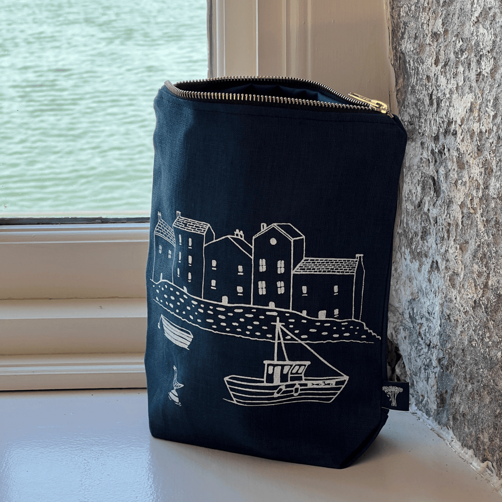 Dark Navy toiletry bag with white illustrations of a coastal scene on a windowsill from Helen Round.