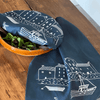 Navy blue tea towel with white boat and house pattern draped over a wooden surface with a bowl of salad covered with a matching navy blue linen bowl cover.
