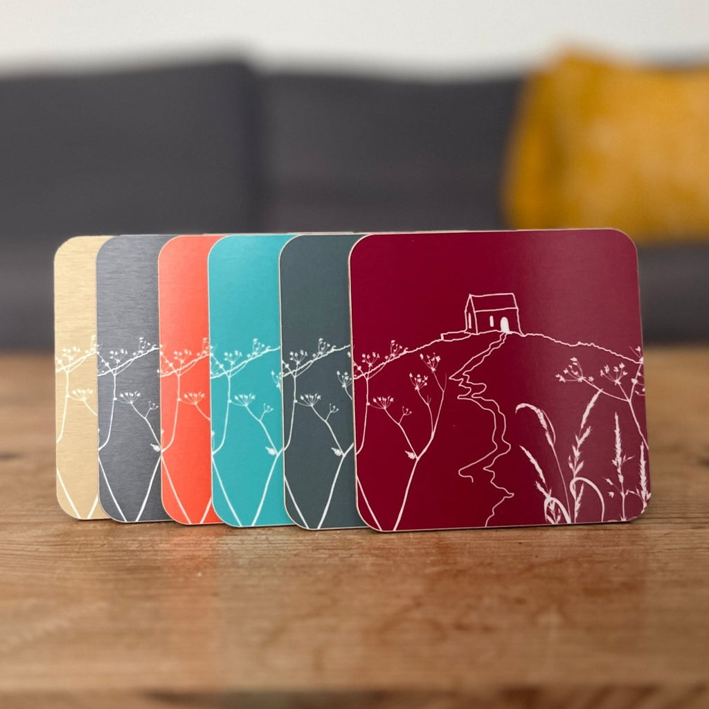 Six colourful  coasters with Rame Head design on a wooden surface from Helen Round.