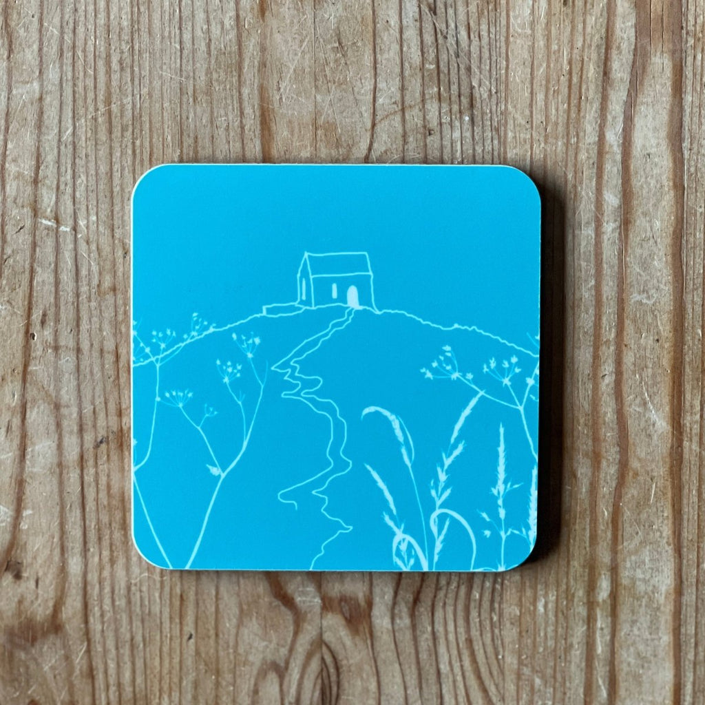 Tuquoise blue coaster with white Rame Head design on a wooden surface from Helen Round.