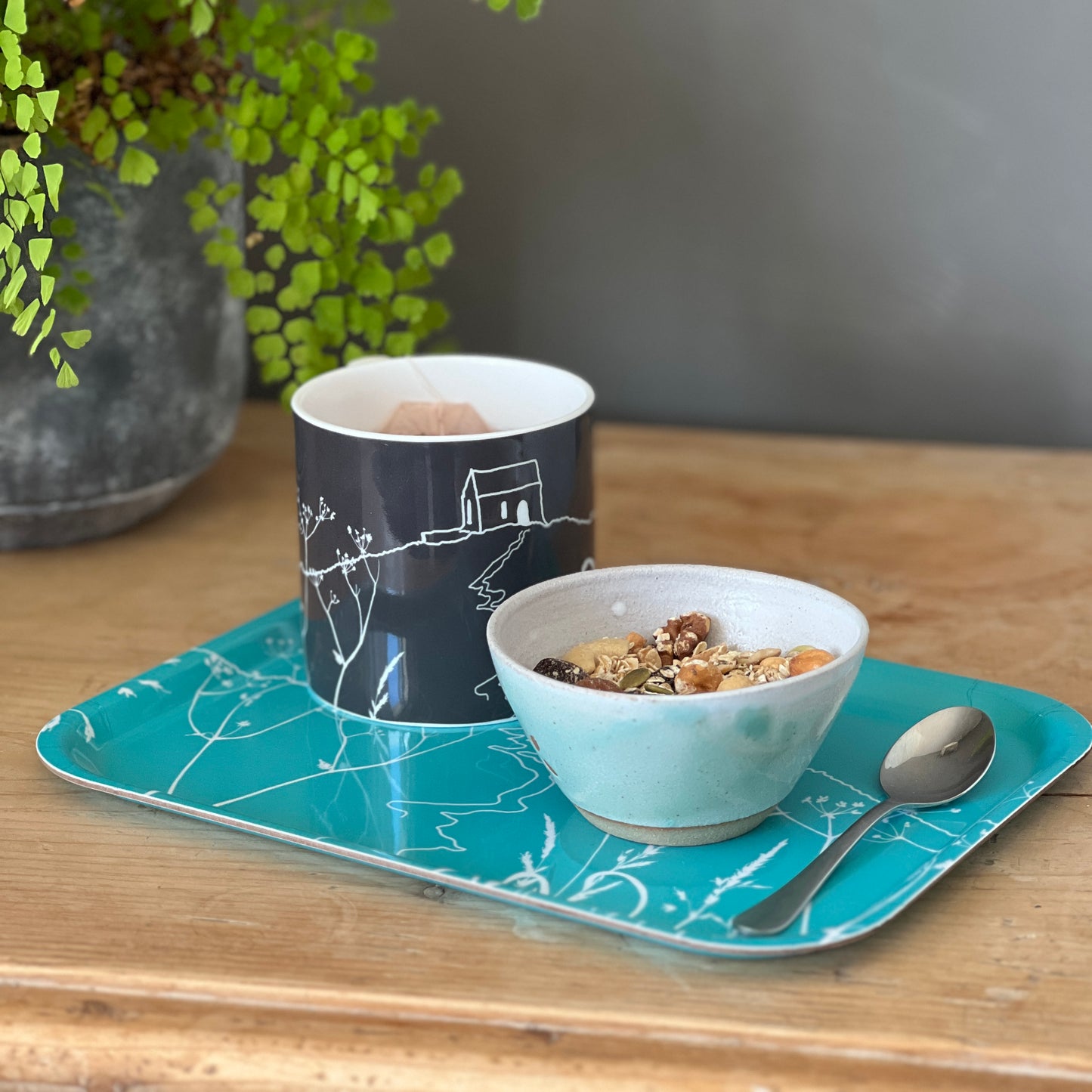 A blue rectangular tray with rounded corners, featuring a white line art illustration of Rame Head from Helen Round 