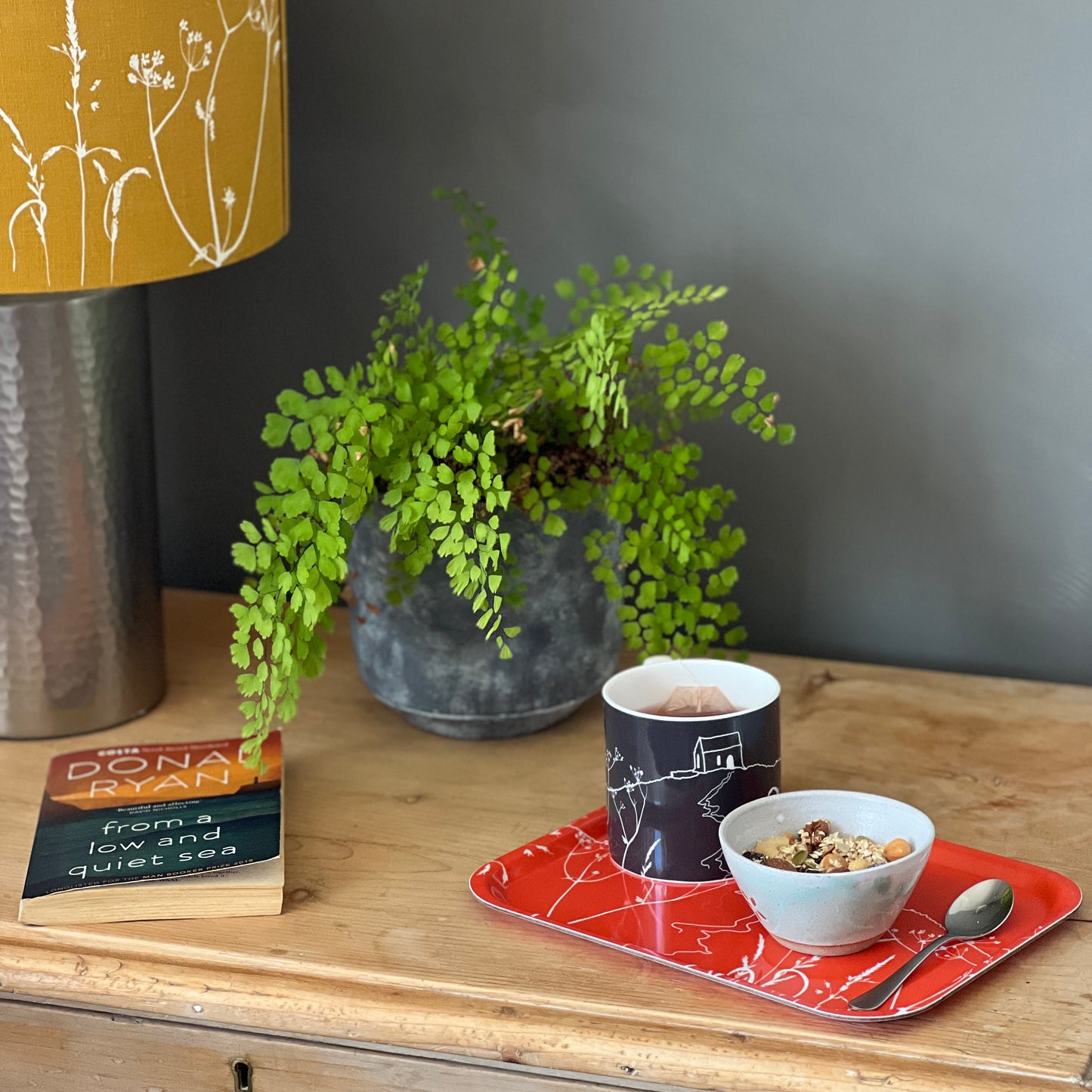 A Orange rectangular tray with rounded corners, featuring a white line art illustration of Rame Head from Helen Round