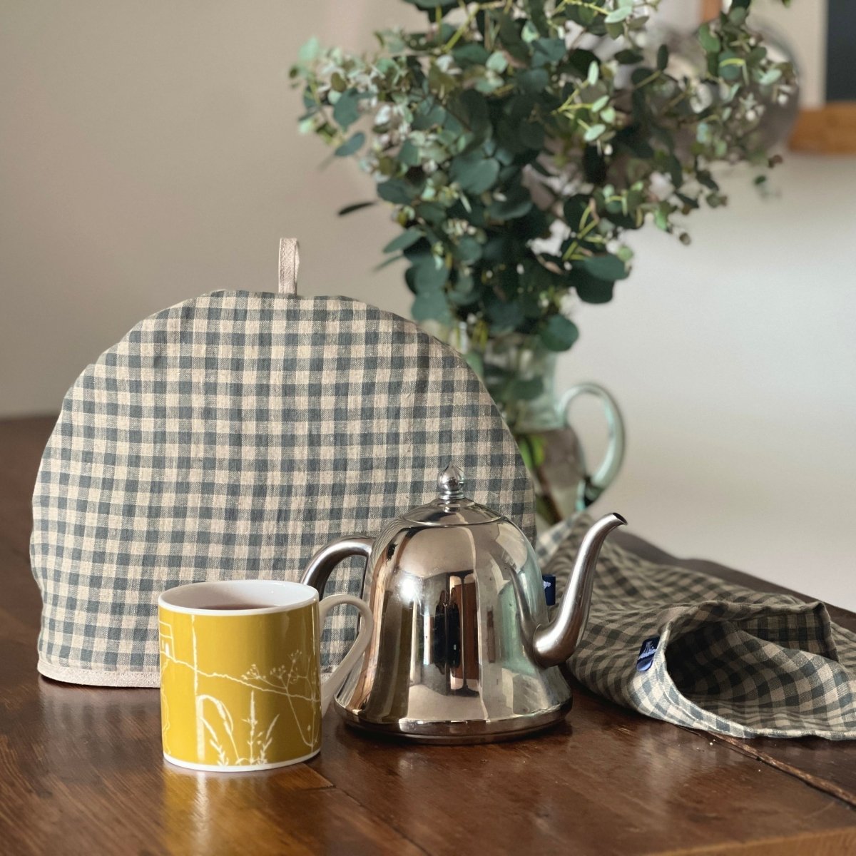 Sea Green Check Linen Tea Cosy with Chartreuse Rame Head Mug and Sea Green Check Linen Tea Towel on a table from a collection by Helen Round