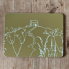 Decorative tablemat with white Rame Head design on a green background, placed on a wooden surface from Helen Round