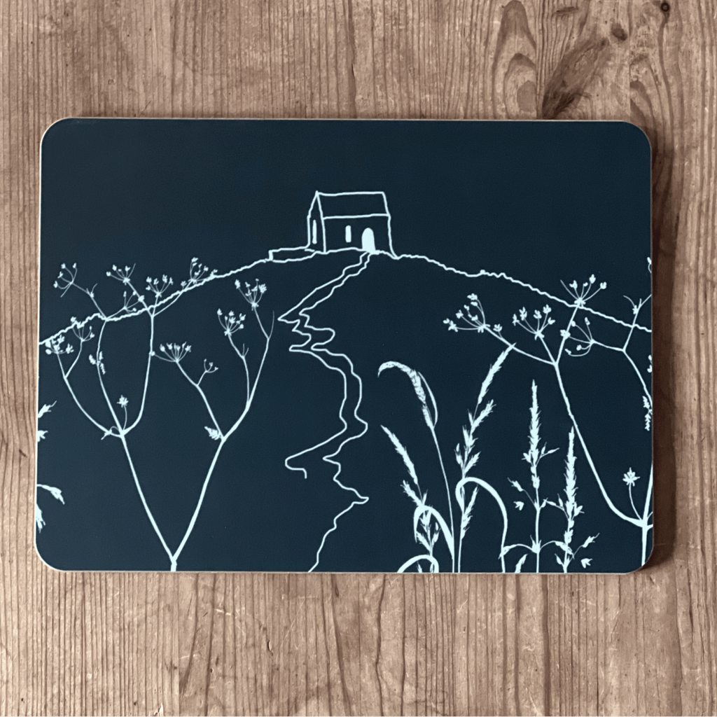 Tablemat with white Rame Head design on a dark blue/black background placed on a wooden surface from Helen Round.