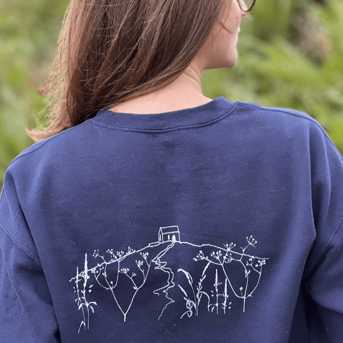 A  navy blue crewneck sweatshirt with 'RAME HEAD' printed in white on the chest With an illustration of Rame Head on the back from Helen Round