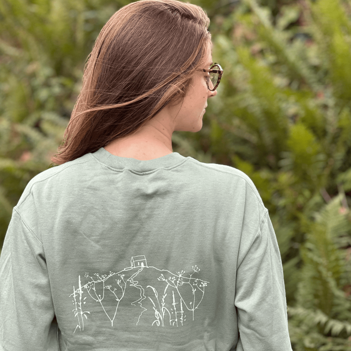 A  Sage Green  crewneck sweatshirt with 'RAME HEAD' printed in white on the chest With an illustration of Rame Head on the back from Helen Round