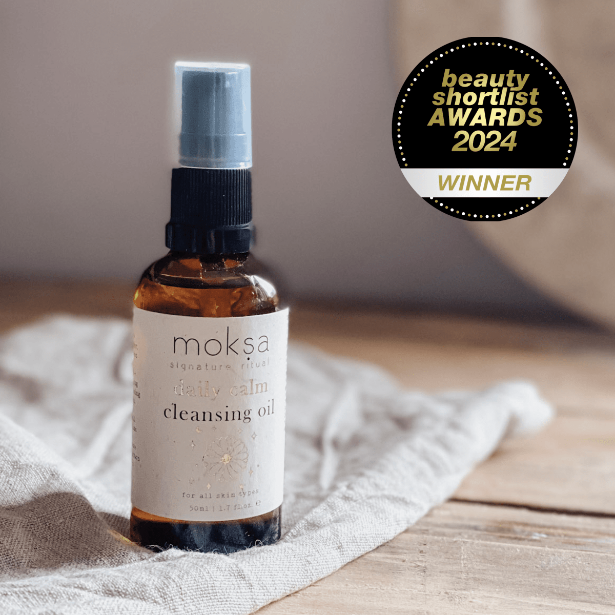 Bottle of moksa face calm cleansing oil on a wooden surface with an award badge in the corner.