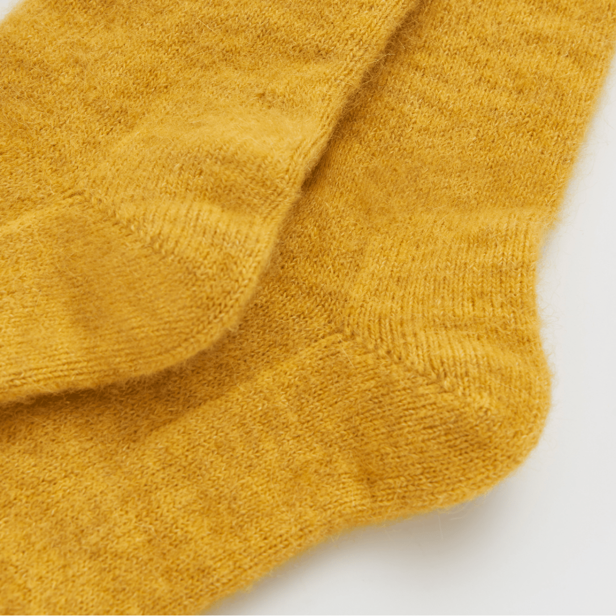 Pair of mustard yellow socks on a light gray background