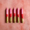 Five pink and gold candles arranged in a row on a pink background