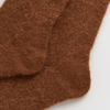 Brown knitted socks on a light gray background