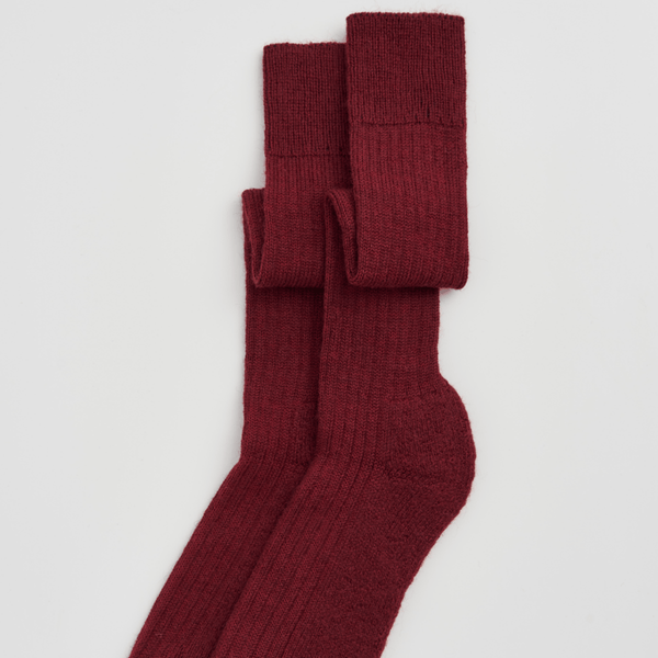 Pair of burgundy socks on a light gray background