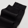 Black merino wool socks on a light grey background