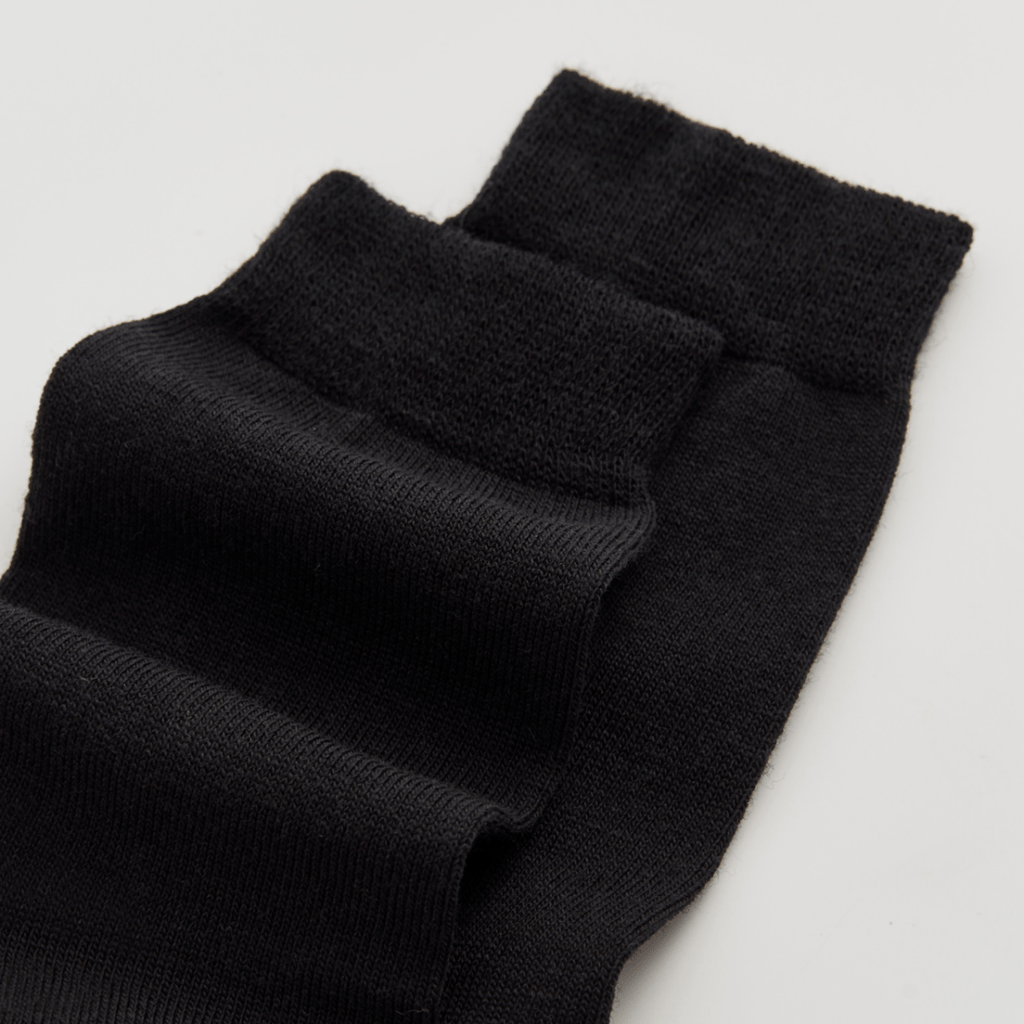 Black merino wool socks on a light grey background
