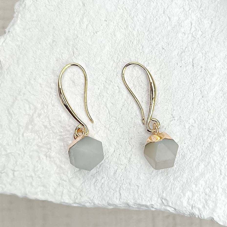 Pair of gold earrings with grey gemstones on a white fabric background sold by Helen Round