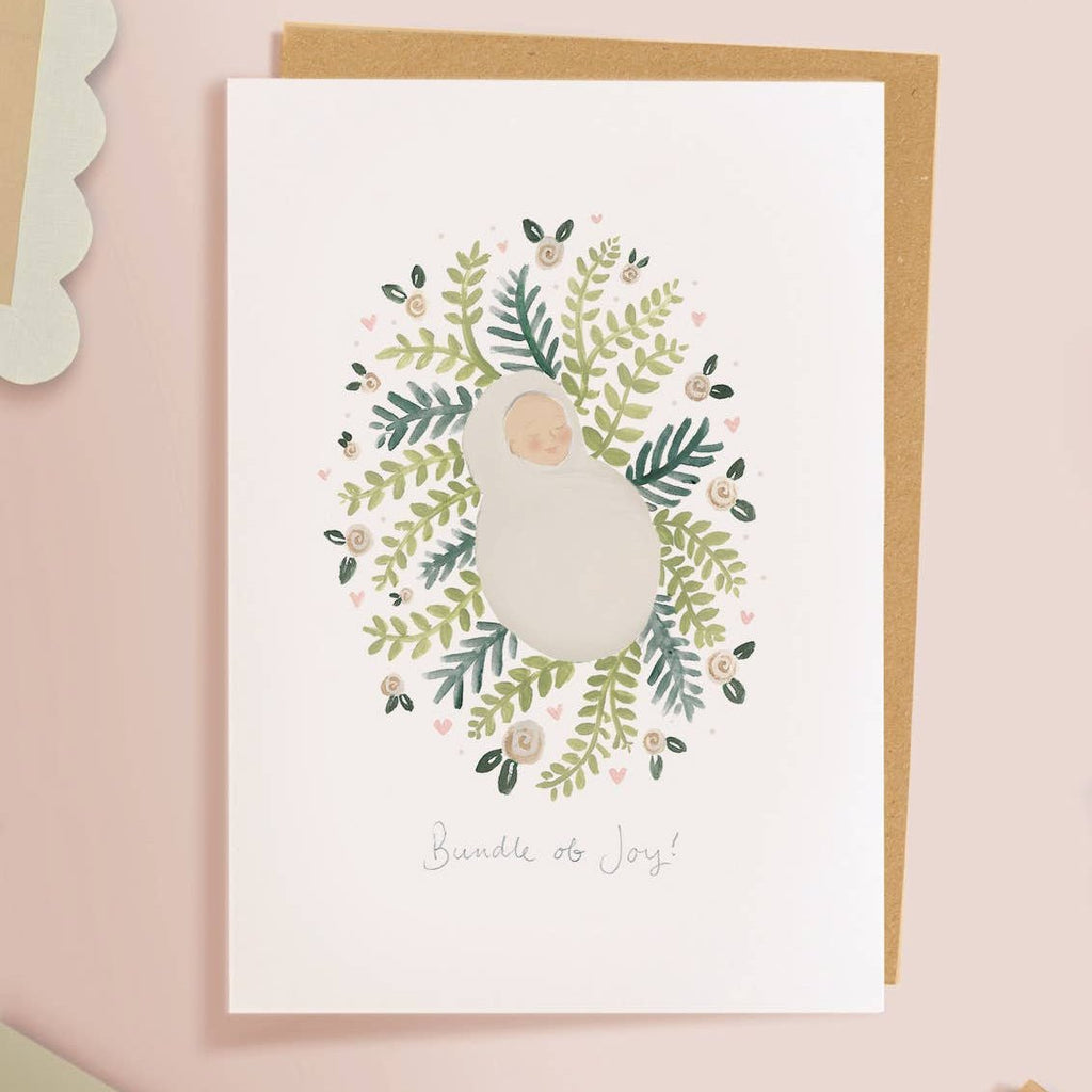 Framed artwork of a wreath with a baby illustration on a pink background  sold by Helen Round