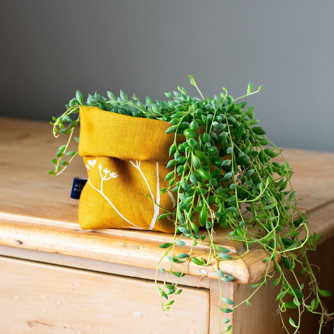 Linen storage bucket with plant in mustard colour